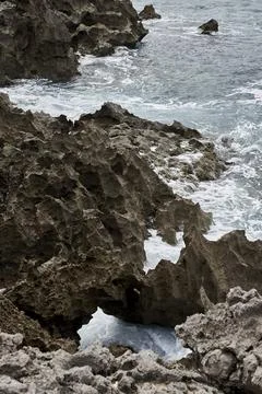 Waves breaking on the rocks at the shore of the beach Stock Photos