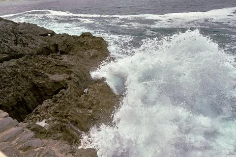 Waves breaking on the rocks at the shore of the beach Stock Photos