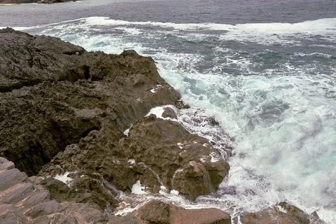 Waves breaking on the rocks at the shore of the beach Stock Photos