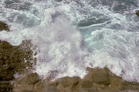 Waves breaking on the rocks at the shore of the beach Stock Photos