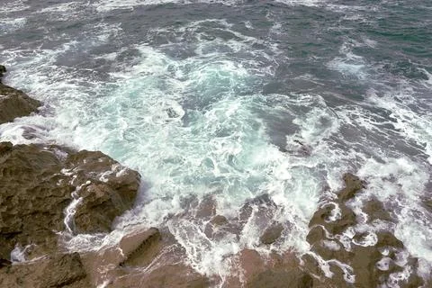 Waves breaking on the rocks at the shore of the beach Stock Photos