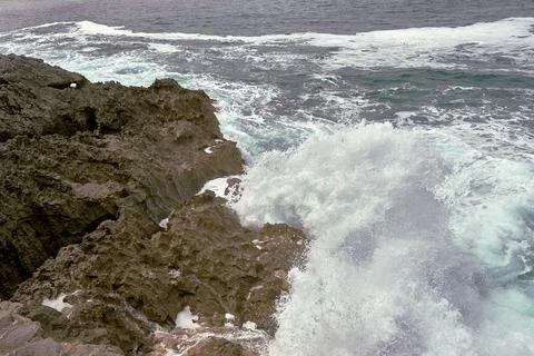 Waves breaking on the rocks at the shore of the beach Stock Photos
