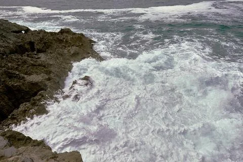 Waves breaking on the rocks at the shore of the beach Stock Photos