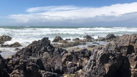 Waves breaking onto the rocks on a sunny day Stock Footage 101483145