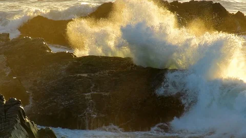Waves breaking onto rocks at sunrise. Video stock 88509318