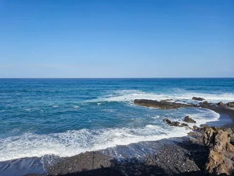 Waves Breaking on Rocky Coast Under Clear Sky Stock Photos
