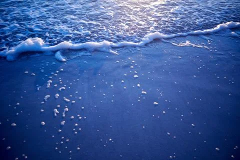 Waves breaking on sandy beach Stock Photos
