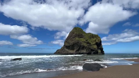 Waves breaking on sandy beach by rock island on dramatic sky sunny summer day Stock Footage 247896814