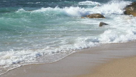 Waves breaking on sandy beach with rocks in background, sunny day in Portugal. Stock Footage 273656721