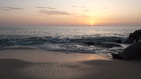 Waves breaking on sandy beach at sunset in slow motion. Sun on horizon Video stock 115996892