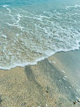 Waves breaking on sandy shore at midday in a beach location with clear wate.. Fotos Stock