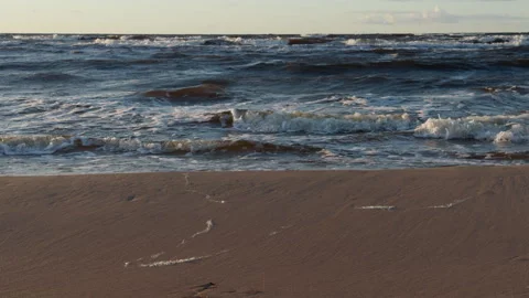 Waves breaking on sandy shoreline with foamy surf and calm horizon under soft Stock Footage 346558504
