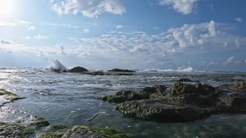 Waves breaking onto the shore and moss covered rocks.Storm waves in the sea. Stockbeeldmateriaal 196290625