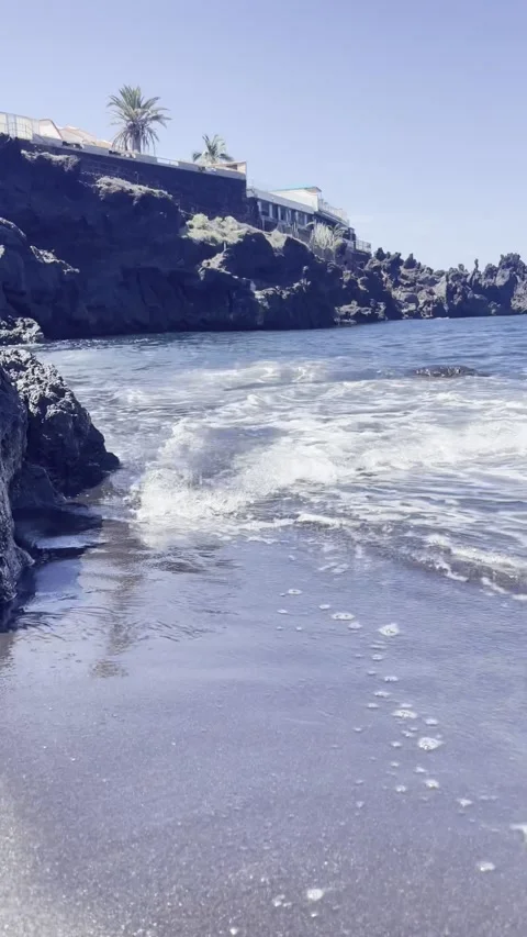 Waves breaking on the shore of the beach with black volcanic sand 動画素材 250113453