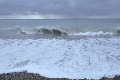 Waves breaking on the shore on small pebble beach Stock Photos