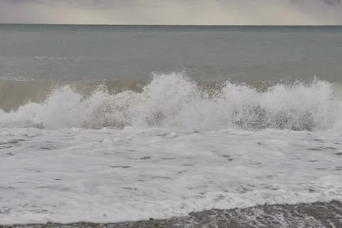 Waves breaking on the shore on small pebble beach Stock Photos