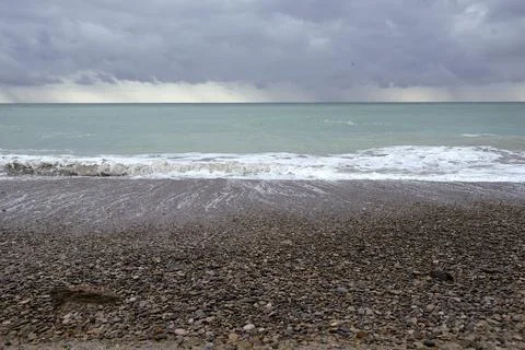 Waves breaking on the shore on small pebble beach Stock Photos
