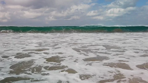Waves breaking on the shore on a windy day 스톡 동영상 128271137