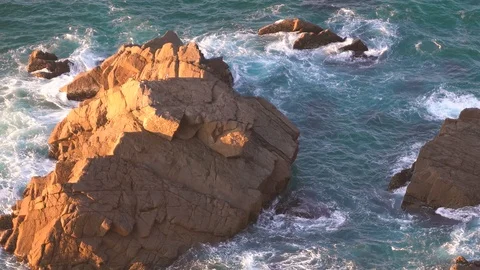 Waves breaking in slow motion against two huge boulders in the water Stock Footage 110760124