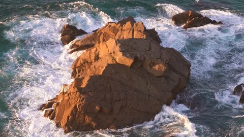 Waves breaking in slow motion against a huge boulder in the water Stock Footage 110760270