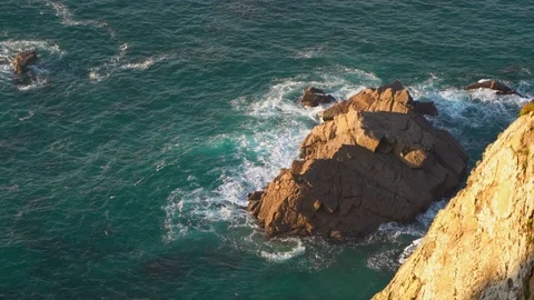 Waves breaking in slow motion against two huge boulders in the water Stock Footage 110761118