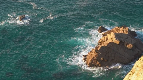 Waves breaking in slow motion against two huge boulders in the water Stock Footage 110761147