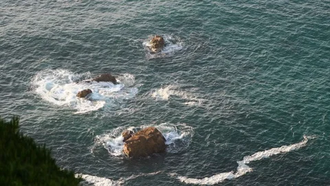 Waves breaking in slow motion against two huge boulders in the water Stock Footage 110761294