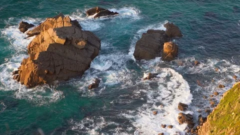 Waves breaking in slow motion against two huge boulders in the water Stock Footage 110761429