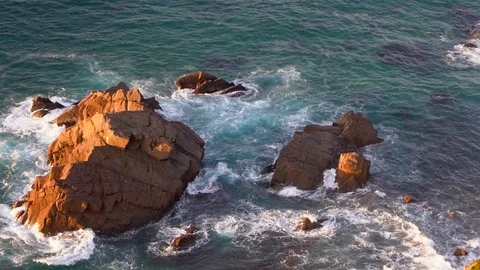 Waves breaking in slow motion against two huge boulders in the water Stock Footage 110761495