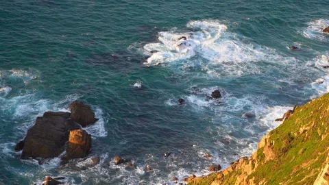 Waves breaking in slow motion against two huge boulders in the water Stock Footage 110761544