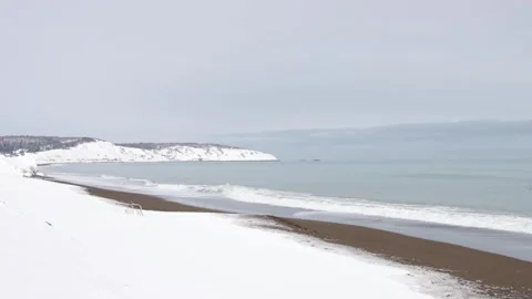 Waves breaking on snow-covered sandy winter beach Stock Footage 303256501