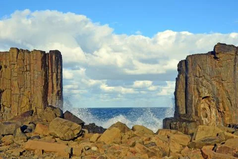 Waves breaking through gap in basalt rock formations on NSW coast Stock Photos