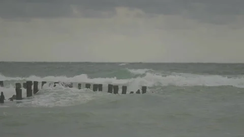 Waves breaking on wooden posts in water Stock Footage 346282194