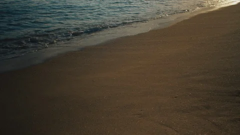 Waves calmly washing on a sandy beach with afternoon sun reflection Stock Footage 119119565