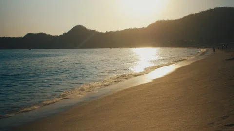 Waves calmly washing on a sandy beach with afternoon sun reflection Stock Footage 119180718