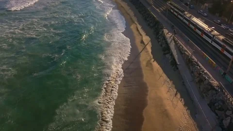 Waves on the coast line very close to town and train passing on sunset Stock Footage 129395387