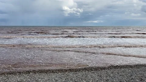 Waves coloured by the red rocks from the Jurassic Period in Devon, England Stock Footage 170234329