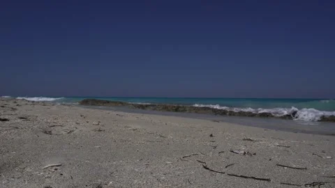 Waves come and go over a cluster of rocks at the edge of the beach Video stock 305239155