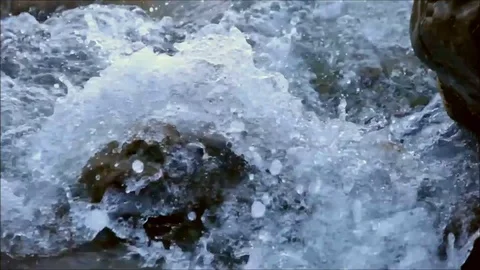 Waves covering a stone creating bubbles under the water Stock Footage 77862912