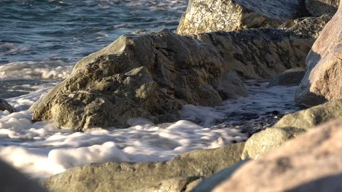 WAVES CRASCHING ON THE ROCKS AT DAWN IN WINTER IN THE LIGURIAN SEA Stockbeeldmateriaal 100690163