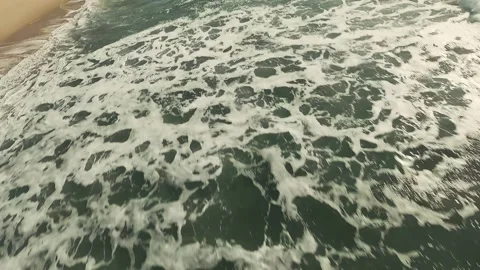 Waves crash against dark, jagged rocks with frothy white spray Stock Footage 339790873