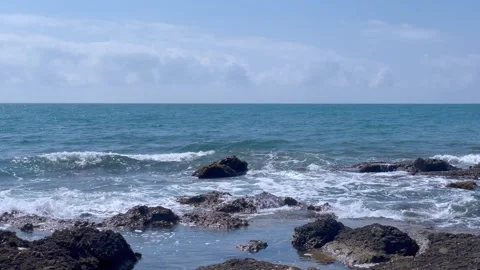 Waves crash against rocks at beach, sea spray. Ocean wave motion, stone coast. Stock Footage 284435412
