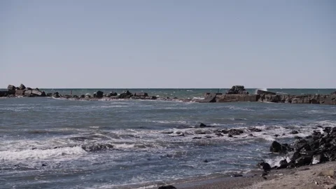 Waves crash against rocks at beach, sea spray in air Stock Footage 319546577