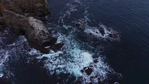 Waves crash against rocks in ocean near rocky coastline at dusk Vidéo 331297222