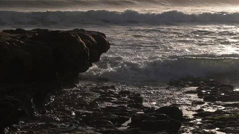 Waves crash against rocks at sunset along the coast during a cloudy evening Stock Footage 327099856