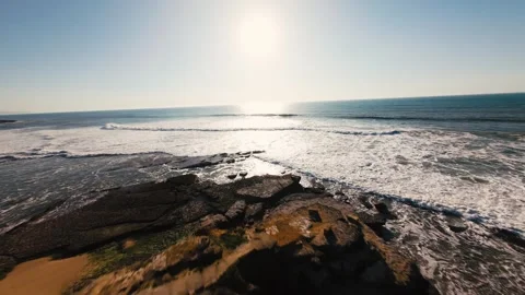 Waves crash against rocky cliffs under bright sun Stock Footage 339787494