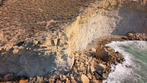 Waves crash against rocky shore at coastal location in warm weather Stock Footage 346017554