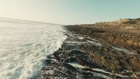 Waves crash against rugged cliffs with wild grasses nearby Stock Footage 339792514