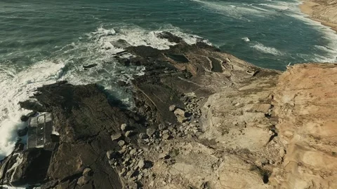 Waves crash against rugged cliffs, sending white foam flying Stock Footage 341825943