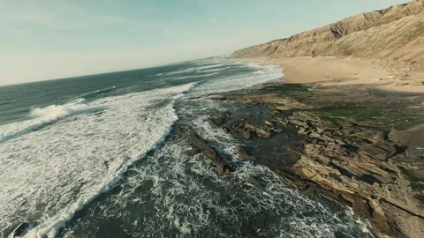 Waves crash against rugged cliffs and sandy shores Stock Footage 341826892